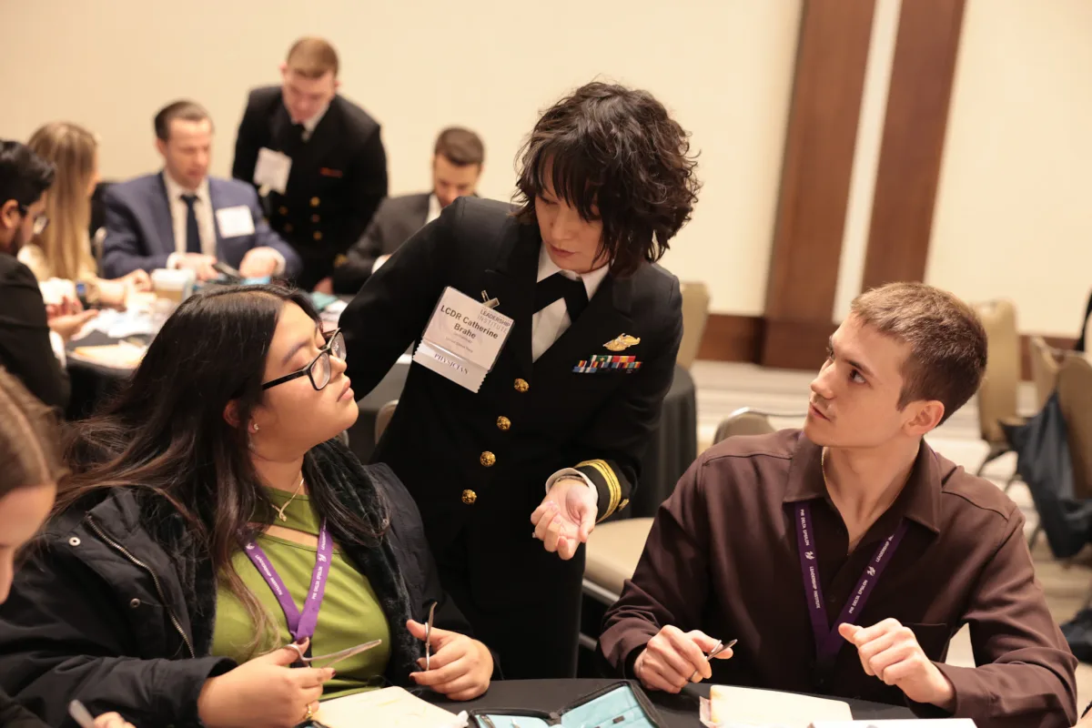 Dr. Brahe mentoring medical students in Navy dress uniform at a dermatology conference